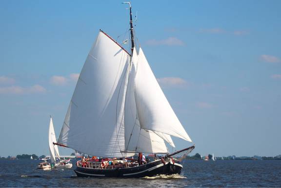 Tjalk Orion under white sails on the water