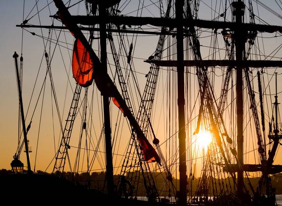 Masts and rigging of sailing ships at sunset